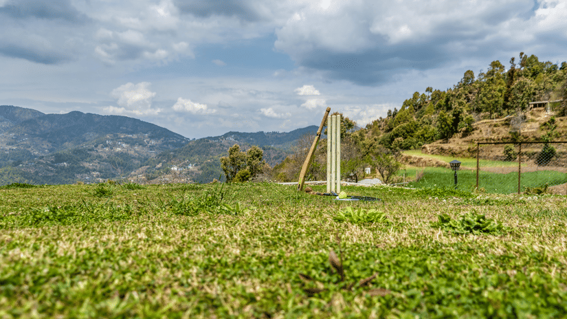 Picture showing a cricket bat, a Set of Stumps, and a red ball along with a Badminton Racquet and a Shuttle.